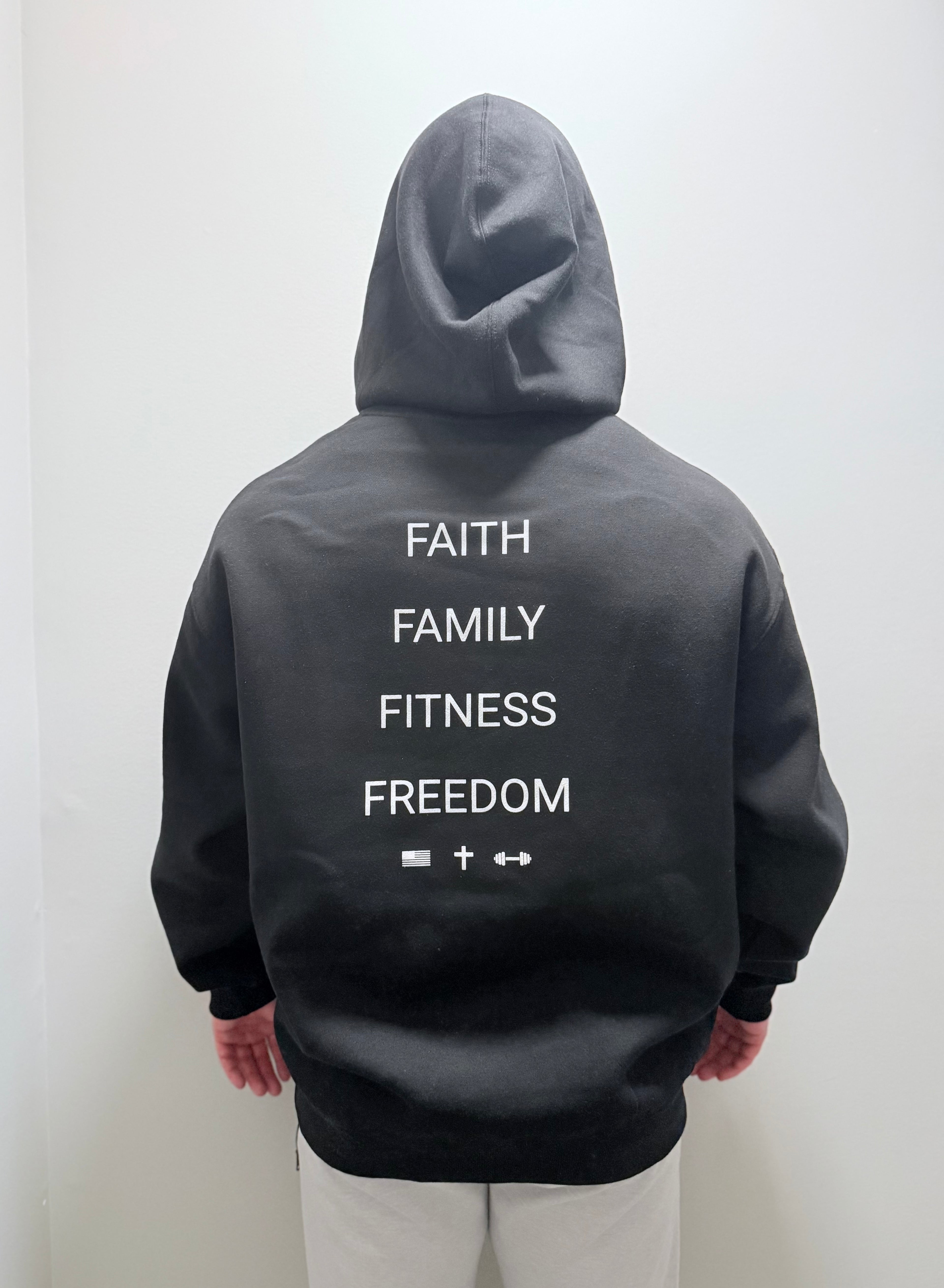 Male model wearing black pullover from the back with Faith Family Fitness Freedom graphic