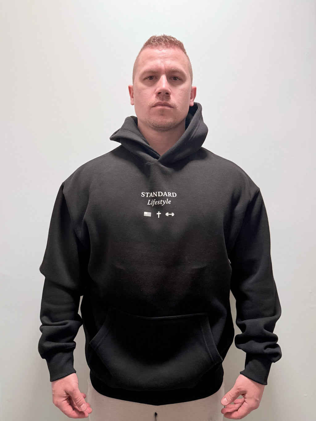 Male model wearing a black pullover front view with small chest logo