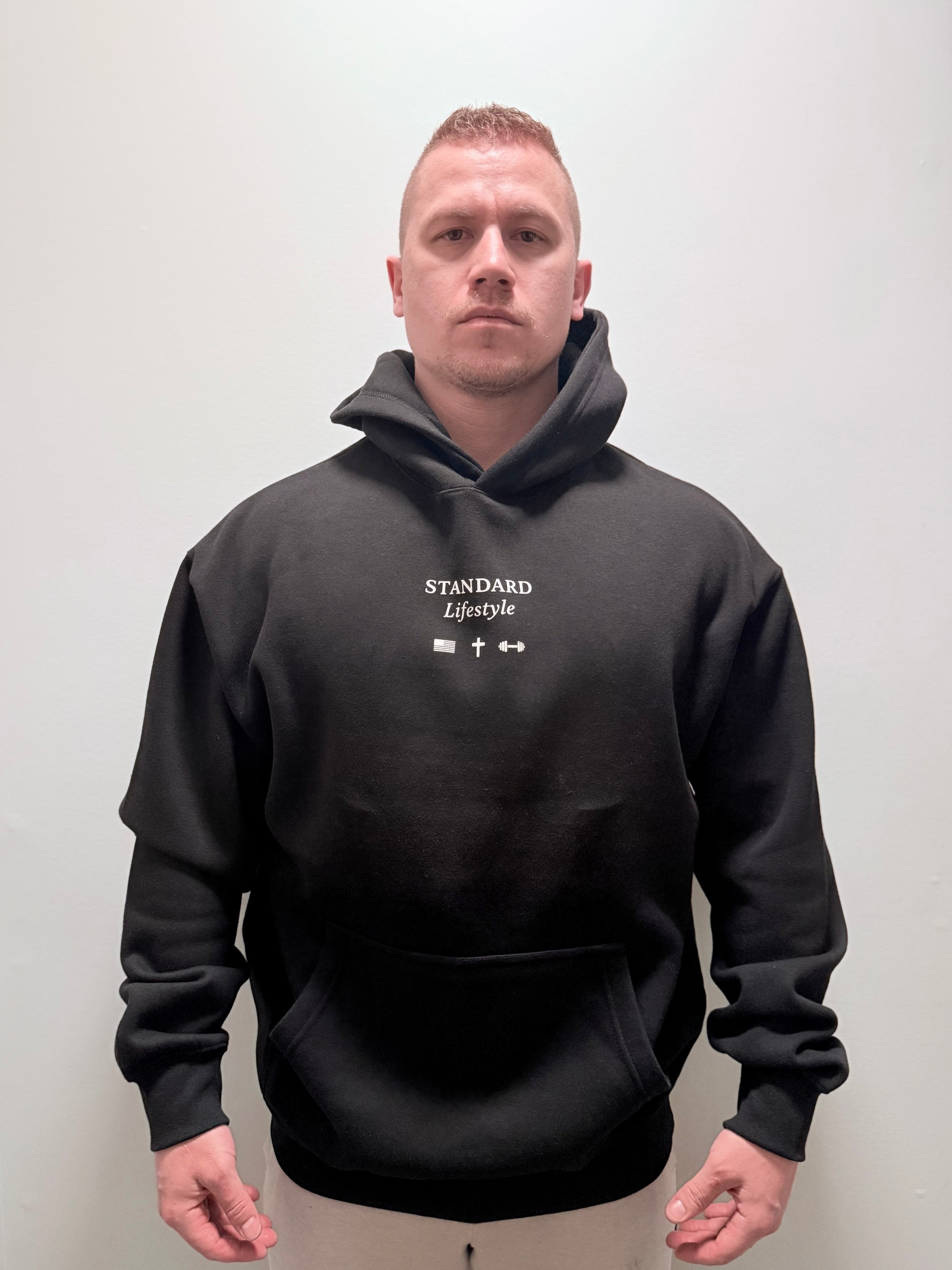 Male model wearing a black pullover front view with small chest logo